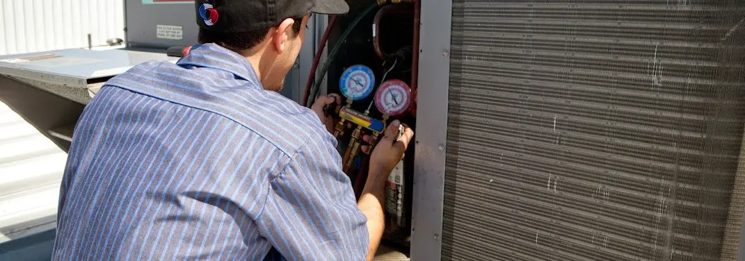 HVAC technician servicing a condenser unit in Stanton